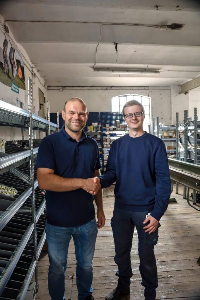 Zwei Mitarbeiter der Höft GmbH geben sich im Lager des Betriebs die Hand